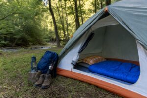 Beginner-friendly sleeping bag laid inside an open tent at a quiet forest campsite.